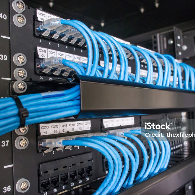 Patchfeld in einem Netzwerkschrank, blaue Kabel sauber nebeneinander gelegt